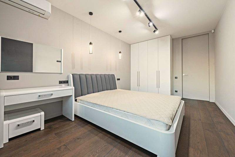 Gri başlıklı beyaz yatak, makyaj masası, tabure, beyaz gardırop, ray spot, koyu parke