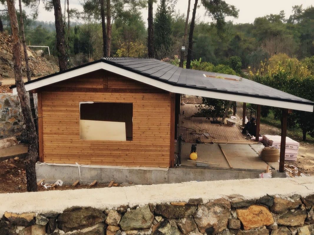 Ahşap kaplı duvarda doğramasız pencere boşluğu, çatı altında ahşap teras döşemesi, beton temel
